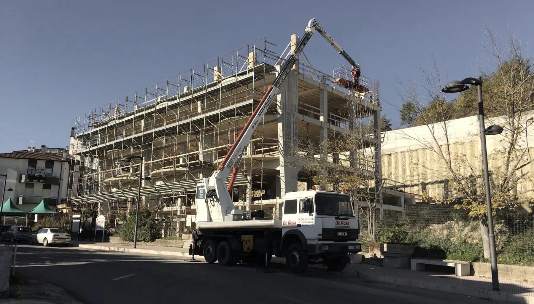 Edificio in cemento armato su più piani con ponteggi e autogru